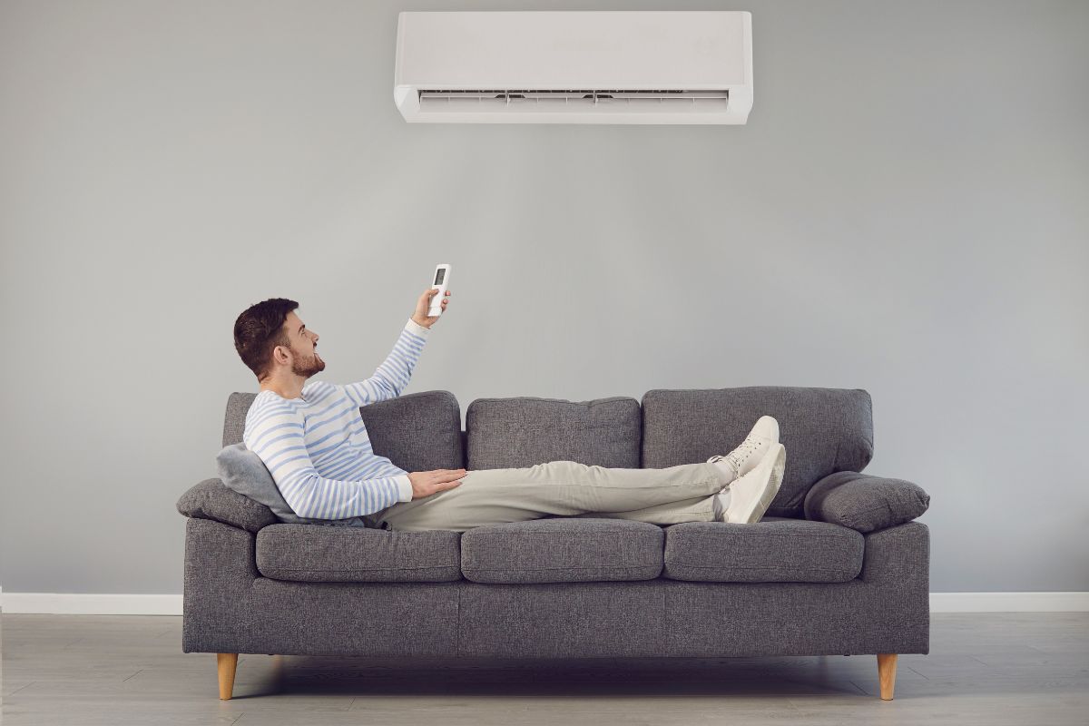 Mężczyzna reguluje temperaturę w domu przy pomocy klimatyzatora