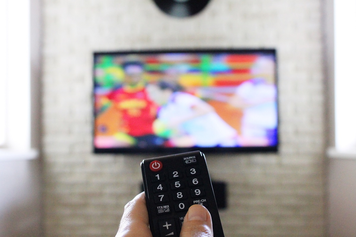 Mężczyzna ustawia tryb energooszczędny w telewizorze
